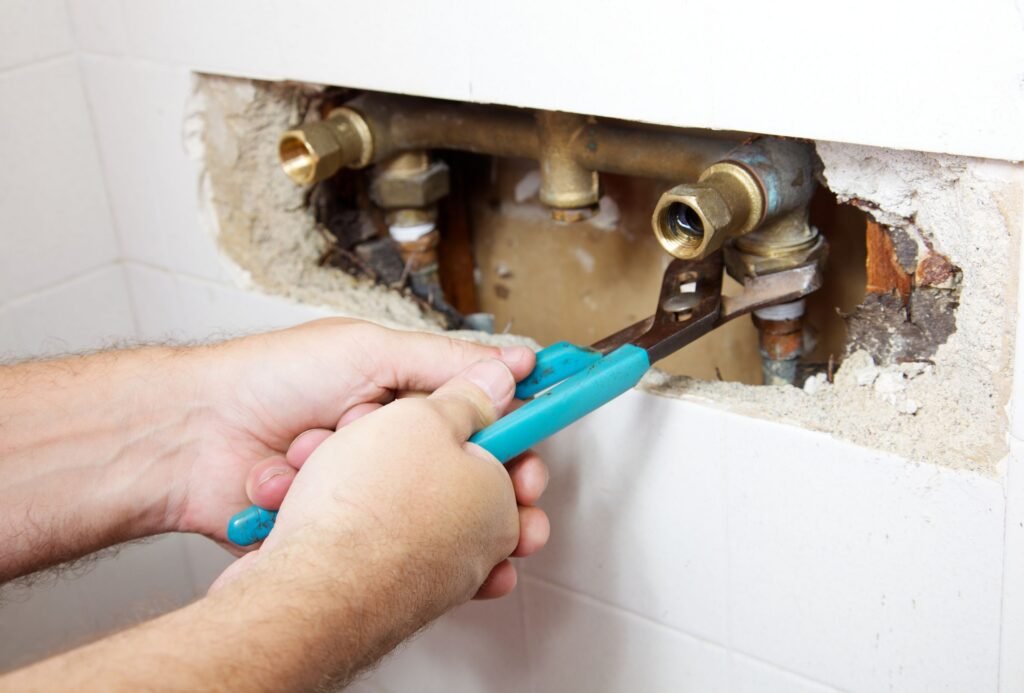 Plumber repairing leaking shower pipes inside bathroom wall in Mooloolaba